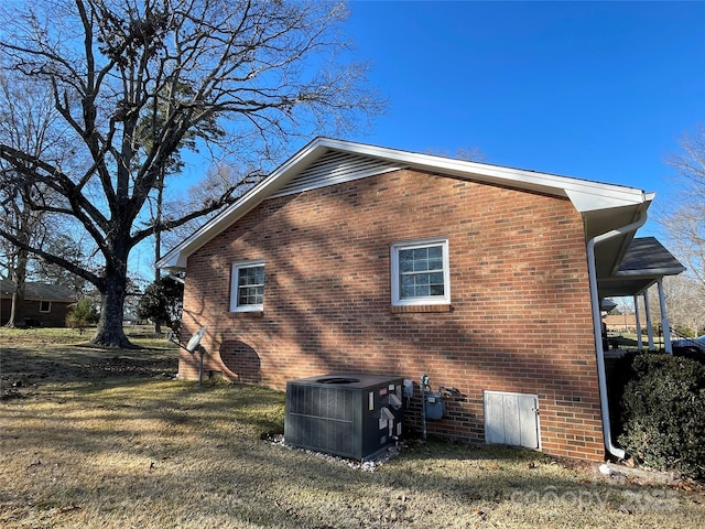 view of side of property with central AC unit and a lawn