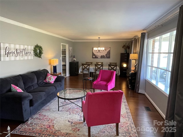 living room featuring crown molding, dark hardwood / wood-style floors, and an inviting chandelier