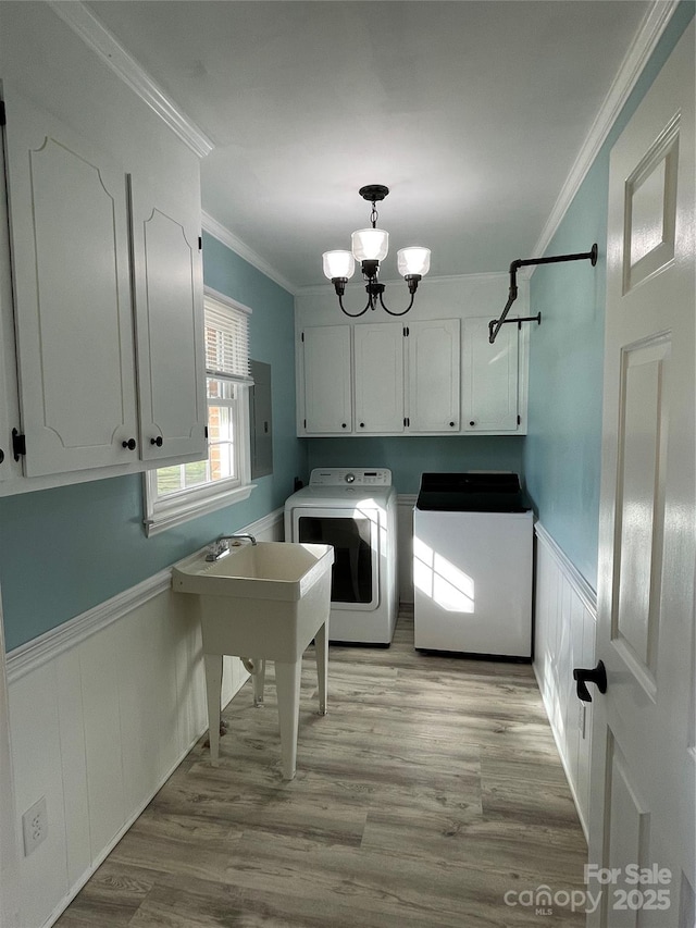 washroom with independent washer and dryer, light hardwood / wood-style floors, crown molding, an inviting chandelier, and cabinets