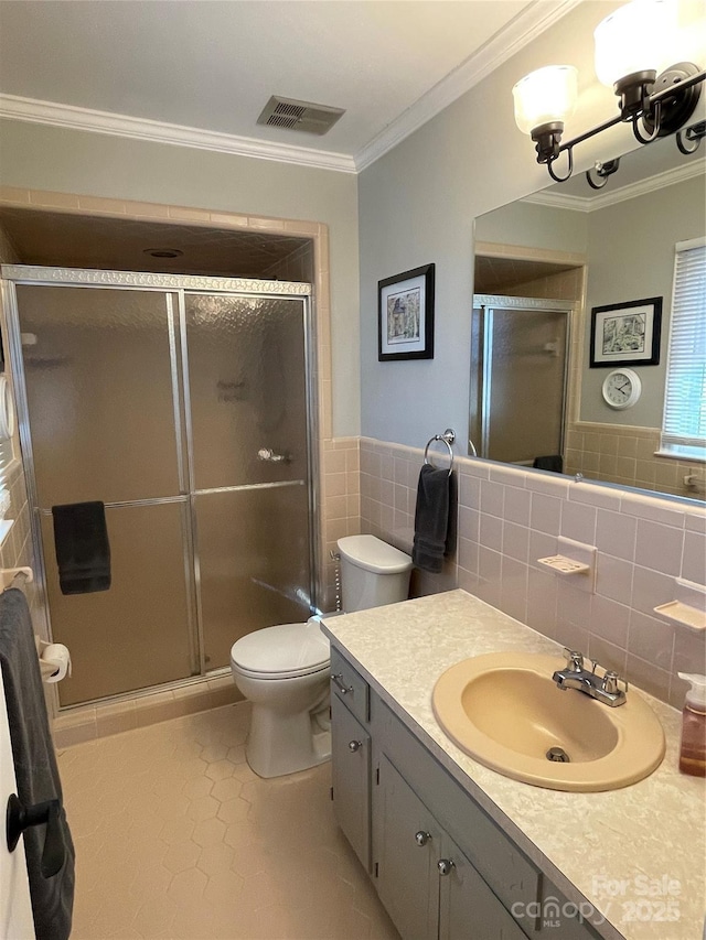 bathroom featuring ornamental molding, tile walls, toilet, and a shower with door