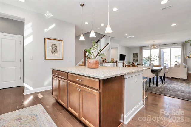 kitchen with open floor plan, hanging light fixtures, visible vents, a center island, and a breakfast bar