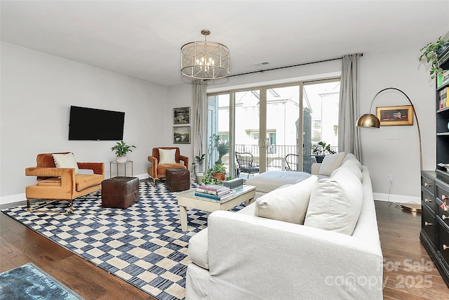 living room featuring baseboards, a chandelier, and dark wood-type flooring