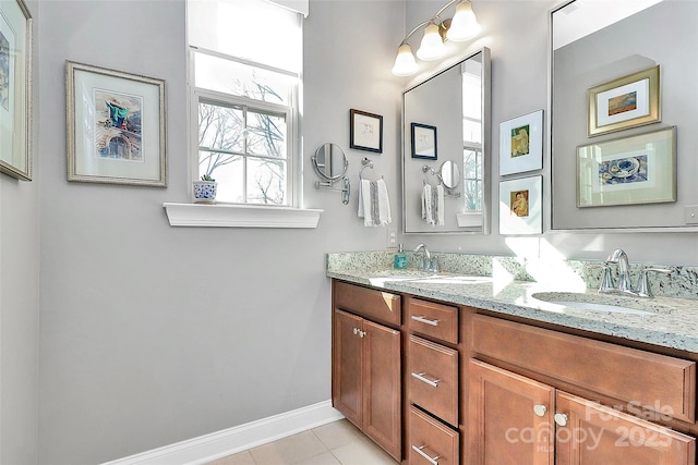 full bathroom featuring double vanity, baseboards, a sink, and tile patterned floors