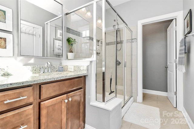 full bathroom featuring a stall shower, vanity, baseboards, and tile patterned floors