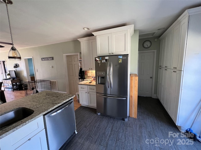 kitchen featuring hanging light fixtures, white cabinetry, appliances with stainless steel finishes, and light stone counters