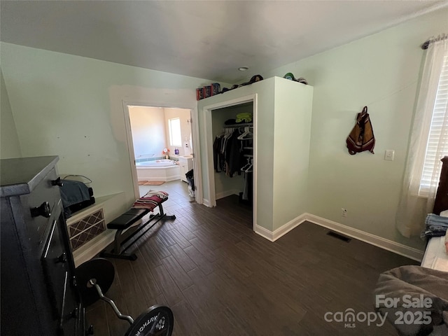 interior space with dark wood-style floors, a closet, visible vents, ensuite bathroom, and baseboards