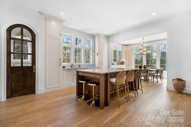 bar with recessed lighting, pendant lighting, light wood-style flooring, and an inviting chandelier