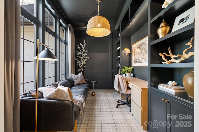 home office featuring built in shelves, built in desk, a decorative wall, and a wealth of natural light