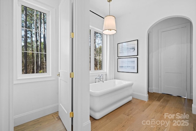 bathroom featuring a freestanding tub, wood finished floors, and baseboards