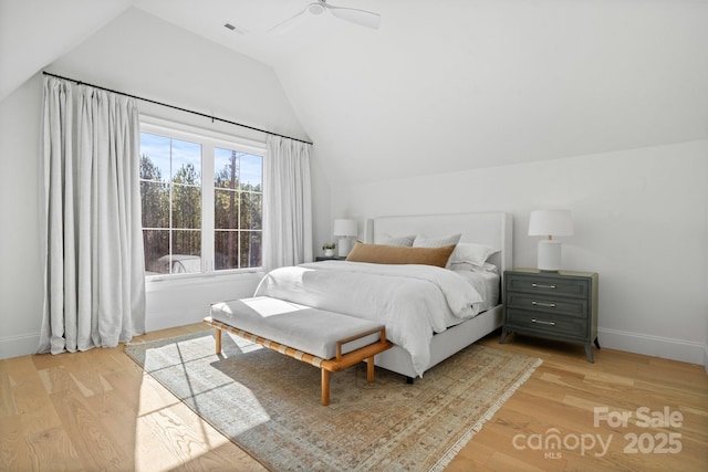 bedroom with light wood-type flooring, visible vents, vaulted ceiling, and baseboards