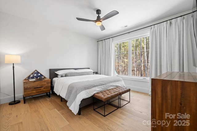 bedroom featuring a ceiling fan, visible vents, light wood-style flooring, and baseboards