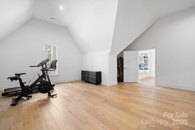 workout area featuring lofted ceiling, light wood-style floors, baseboards, and visible vents