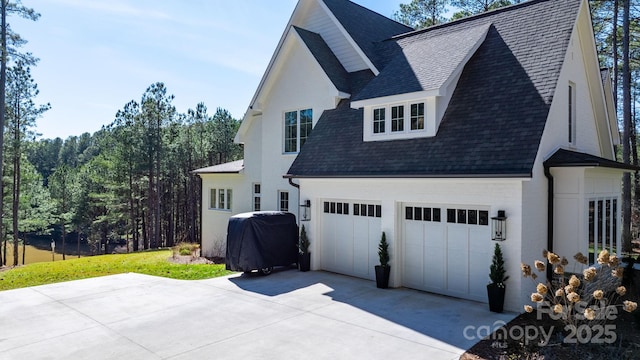 view of front of home with driveway, an attached garage, and roof with shingles