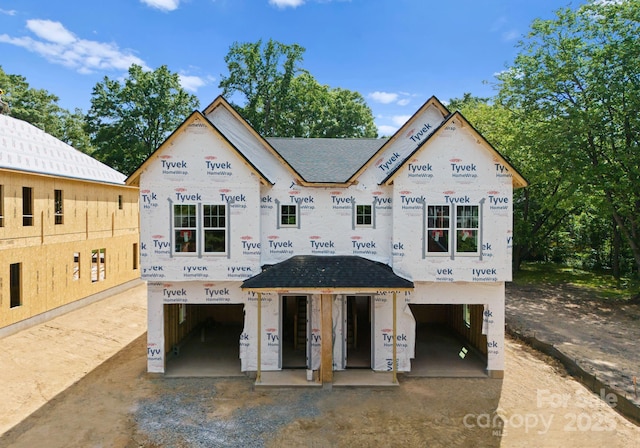 unfinished property featuring a garage and roof with shingles