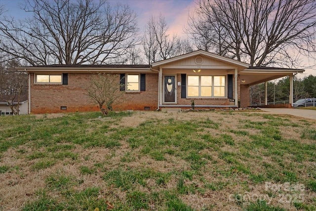 ranch-style home featuring a carport, brick siding, crawl space, and driveway