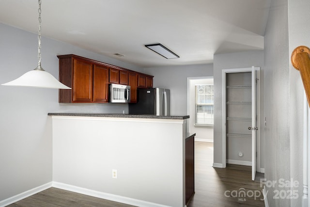 kitchen with kitchen peninsula, pendant lighting, stainless steel appliances, and dark wood-type flooring