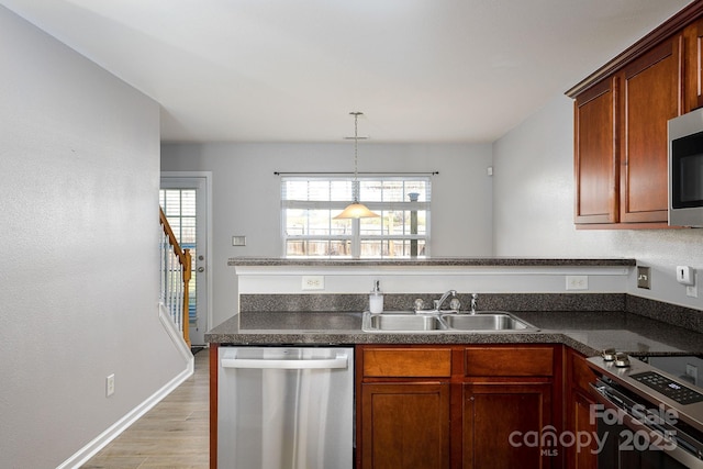 kitchen featuring stainless steel appliances, decorative light fixtures, sink, and light hardwood / wood-style floors