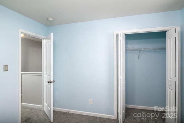 unfurnished bedroom with dark carpet and a closet