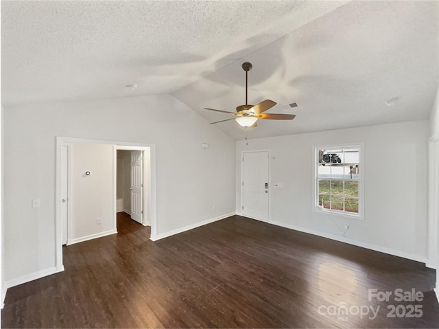 interior space featuring vaulted ceiling, dark wood finished floors, and a textured ceiling