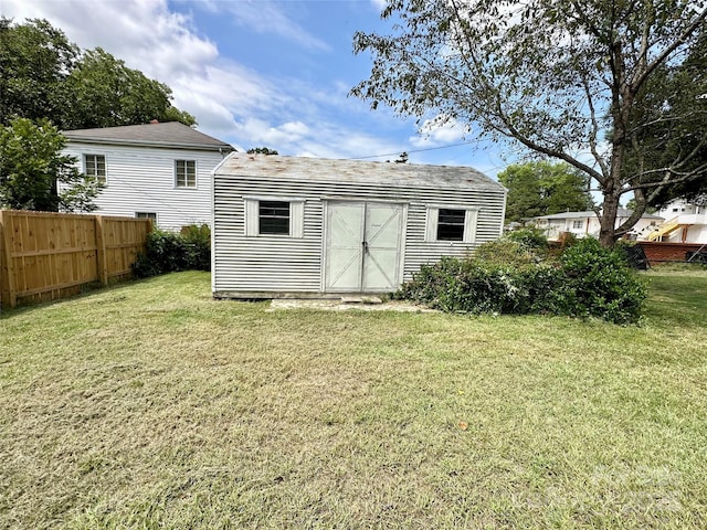 rear view of property featuring a lawn and a storage shed