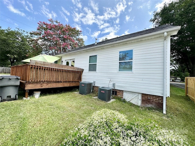 rear view of property featuring cooling unit, a yard, and a wooden deck