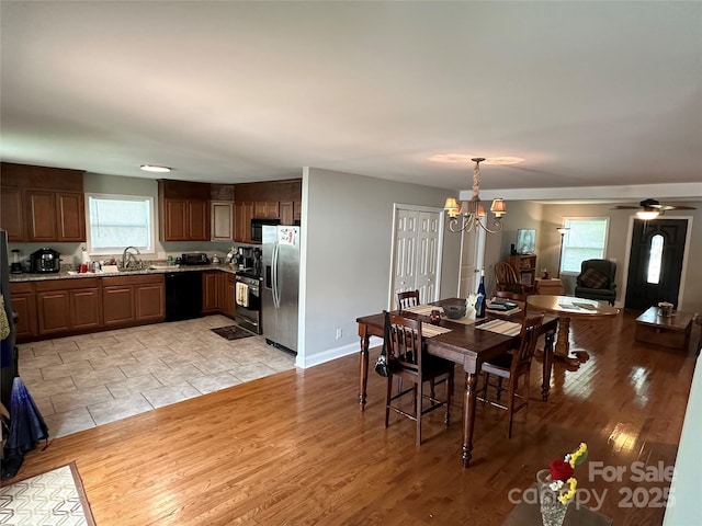 dining room with ceiling fan with notable chandelier, light hardwood / wood-style floors, and sink