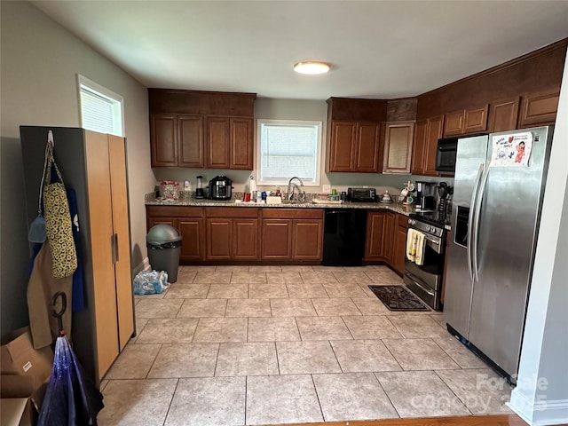 kitchen featuring light tile patterned floors, sink, black appliances, and light stone counters