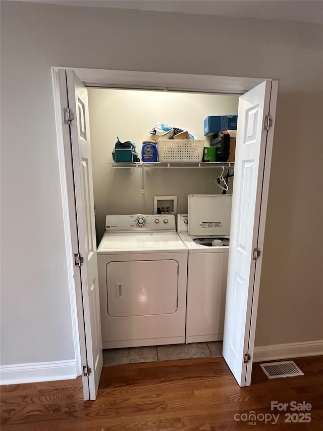 clothes washing area with washer and clothes dryer and hardwood / wood-style floors