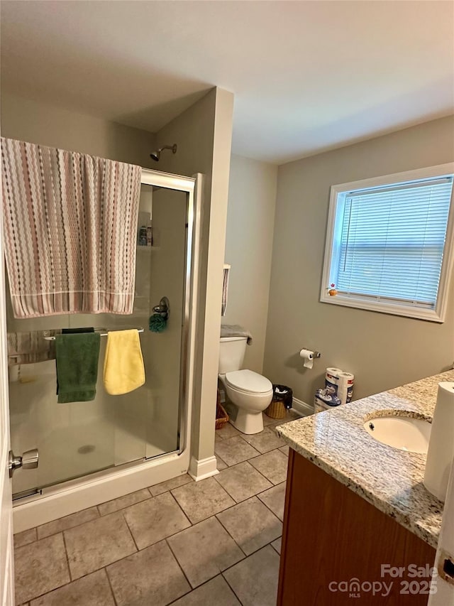 bathroom featuring toilet, a shower with shower door, vanity, and tile patterned flooring