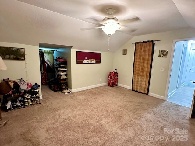 interior space featuring ceiling fan, vaulted ceiling, and light carpet