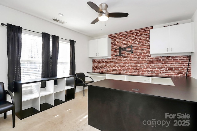 home office featuring ceiling fan, brick wall, and visible vents