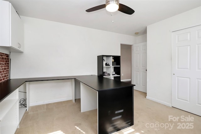 unfurnished office featuring light carpet, ceiling fan, and baseboards