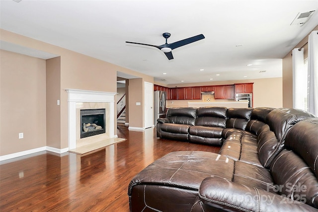 living area with dark wood-type flooring, a high end fireplace, and baseboards