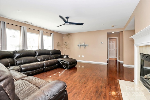 living area featuring a premium fireplace, wood finished floors, visible vents, and baseboards