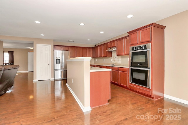 kitchen with appliances with stainless steel finishes, recessed lighting, under cabinet range hood, and light wood-style flooring