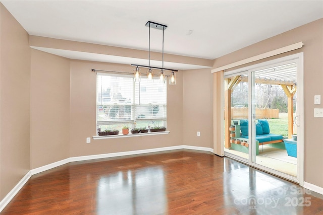 empty room with a wealth of natural light, baseboards, and wood finished floors