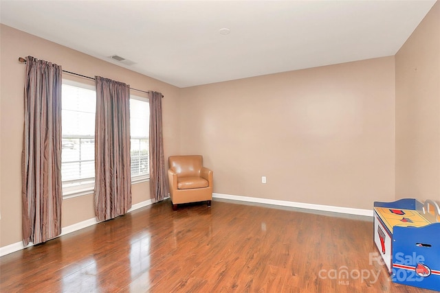 unfurnished room featuring baseboards, visible vents, and wood finished floors