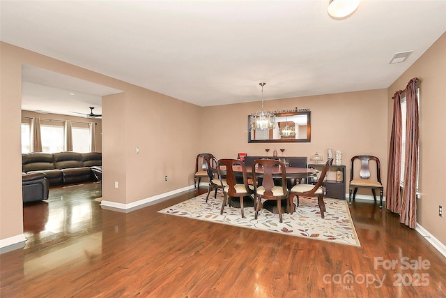 dining space featuring baseboards, visible vents, dark wood-type flooring, and ceiling fan with notable chandelier