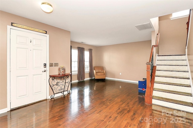 foyer featuring visible vents, stairway, baseboards, and wood finished floors