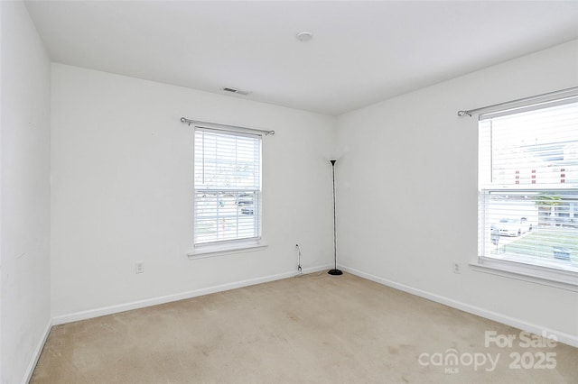 empty room with light carpet, visible vents, and baseboards