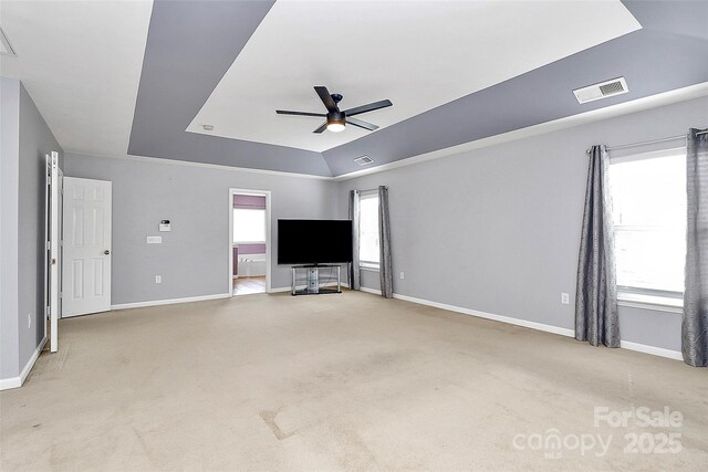 unfurnished living room featuring a raised ceiling, visible vents, ceiling fan, and light carpet