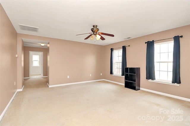 empty room featuring baseboards, visible vents, and light colored carpet