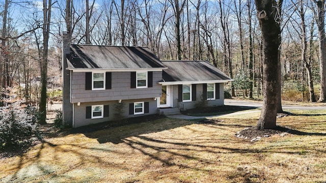 tri-level home featuring a front yard, brick siding, and a chimney