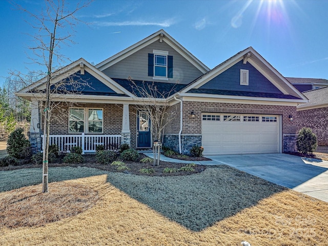 craftsman inspired home featuring driveway, a garage, a porch, and brick siding