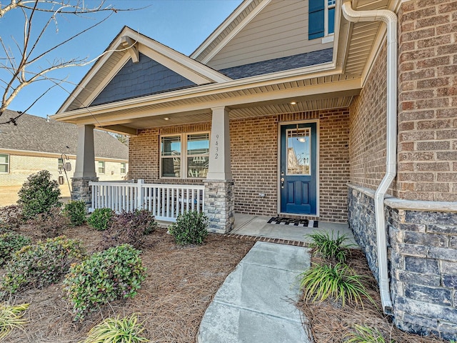 view of exterior entry featuring brick siding and a porch