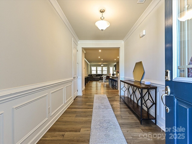 entryway with a wainscoted wall, a decorative wall, dark wood-style flooring, and crown molding