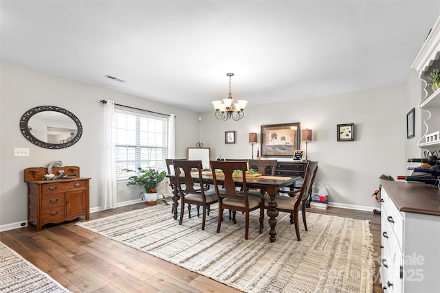 dining room featuring dark wood-style floors, a chandelier, and baseboards