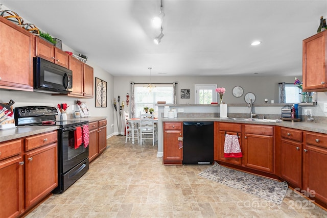 kitchen with pendant lighting, light countertops, brown cabinetry, a sink, and black appliances