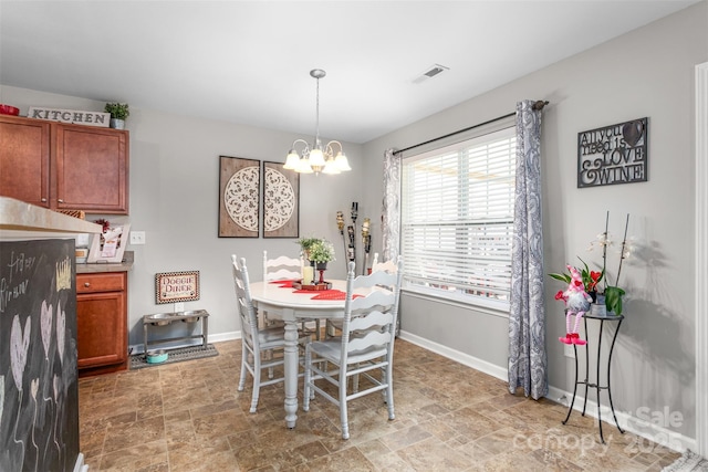 dining area featuring a chandelier, stone finish floor, and baseboards