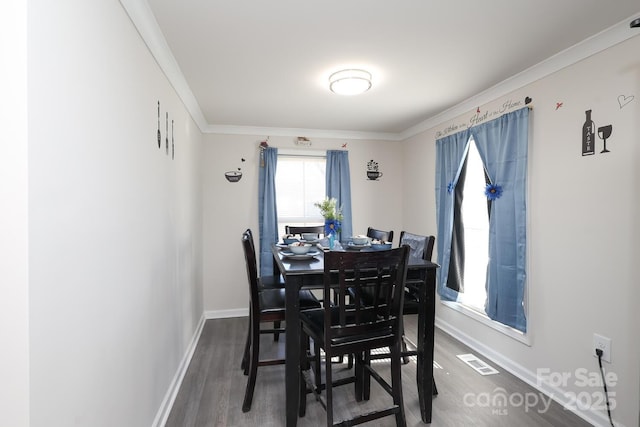 dining space featuring ornamental molding, wood finished floors, visible vents, and baseboards